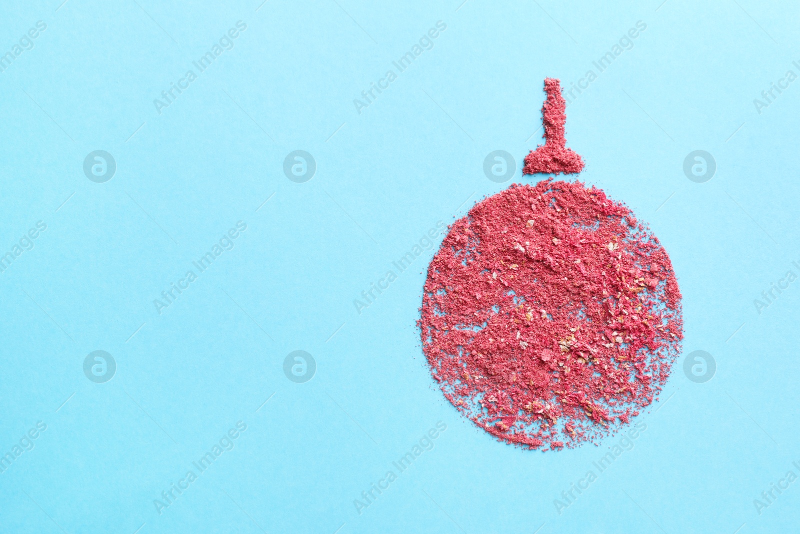 Photo of Christmas ball made with blush on light blue background, top view. Space for text