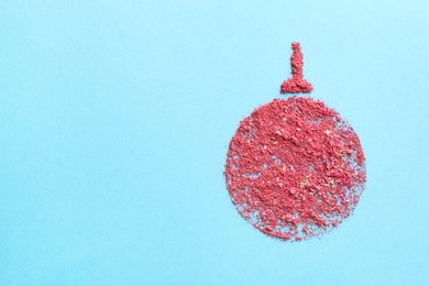 Photo of Christmas ball made with blush on light blue background, top view. Space for text