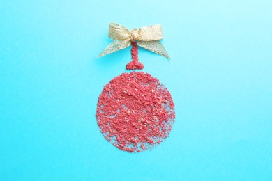 Photo of Christmas ball made with blush on light blue background, top view