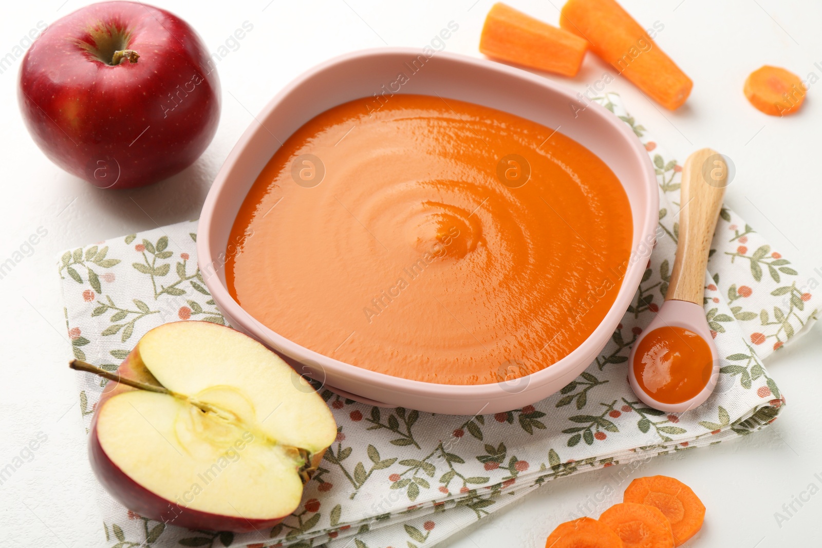 Photo of Delicious baby food in bowl and ingredients on white table