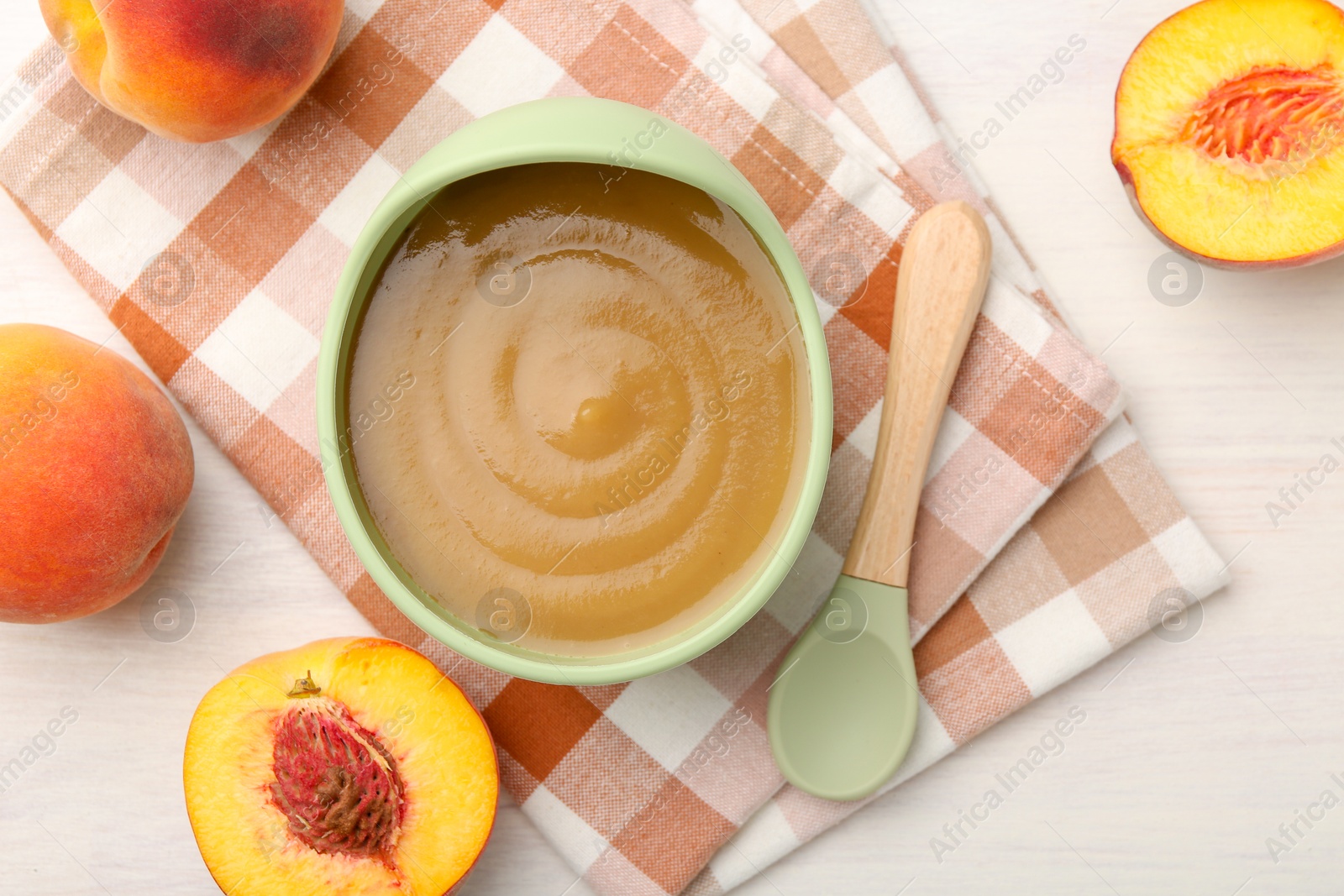 Photo of Delicious baby food in bowl and fresh ingredients on white wooden table, flat lay