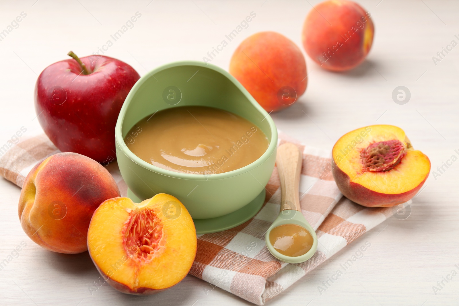 Photo of Delicious baby food in bowl and fresh ingredients on white wooden table