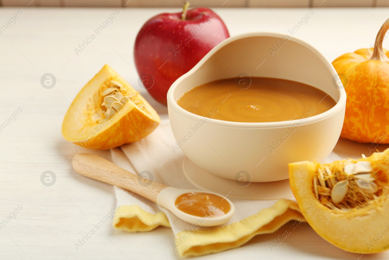 Photo of Delicious baby food in bowl and fresh ingredients on white wooden table