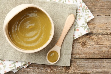 Photo of Delicious baby food in bowl with spoon on wooden table, flat lay