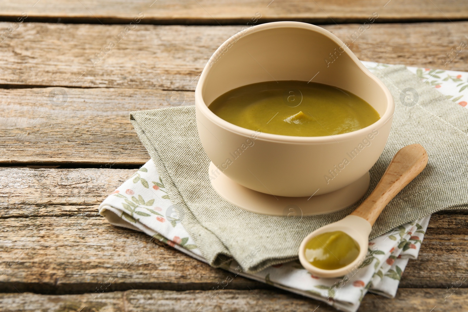 Photo of Delicious baby food in bowl with spoon on wooden table