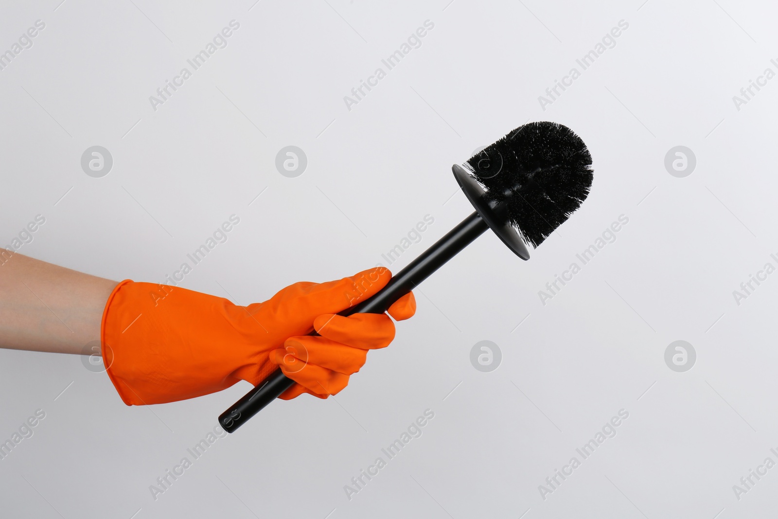 Photo of Woman holding black toilet brush on light background, closeup. Cleaning tool