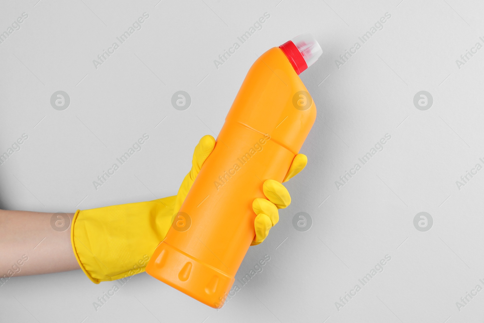 Photo of Woman holding toilet cleaner in bottle on light background, closeup