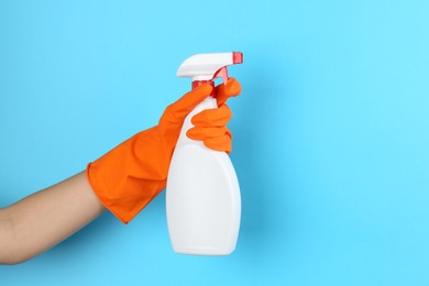 Photo of Woman holding toilet cleaner in spray bottle on light blue background, closeup