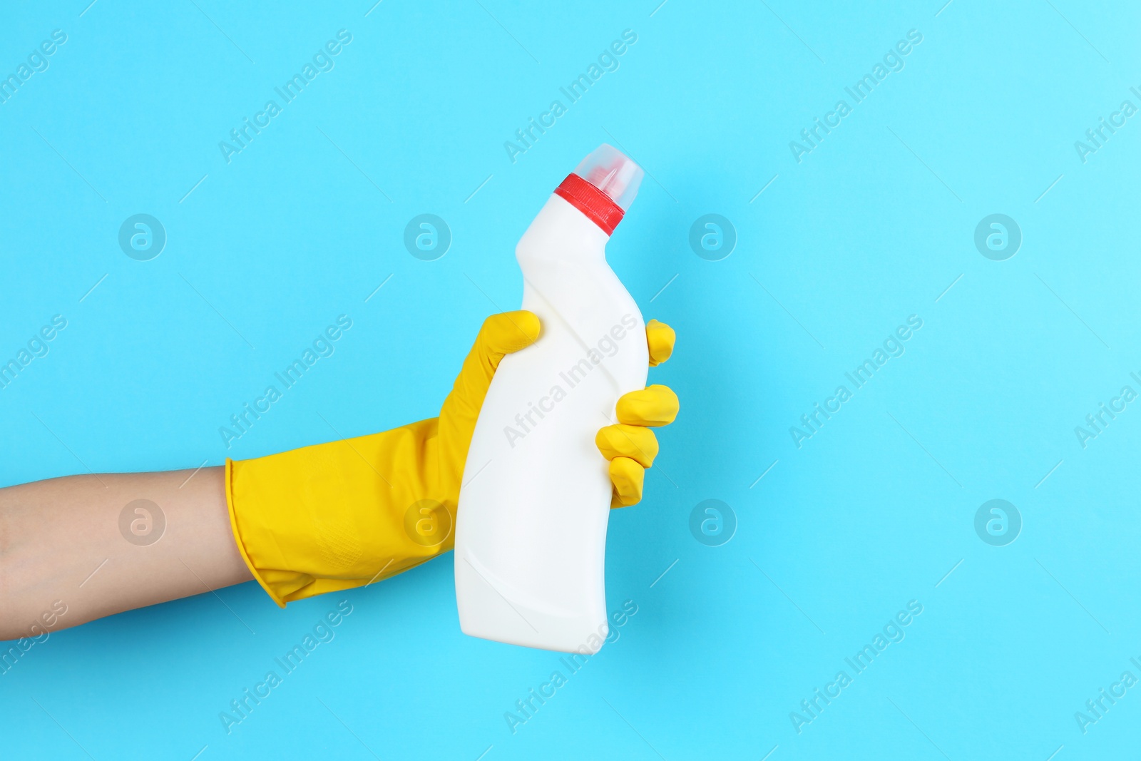 Photo of Woman holding toilet cleaner in bottle on light blue background, closeup