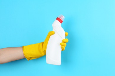 Photo of Woman holding toilet cleaner in bottle on light blue background, closeup