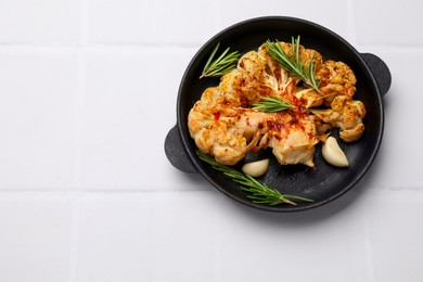 Photo of Delicious baked cauliflower steaks on white tiled table, top view. Space for text