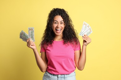 Happy woman with dollar banknotes on yellow background