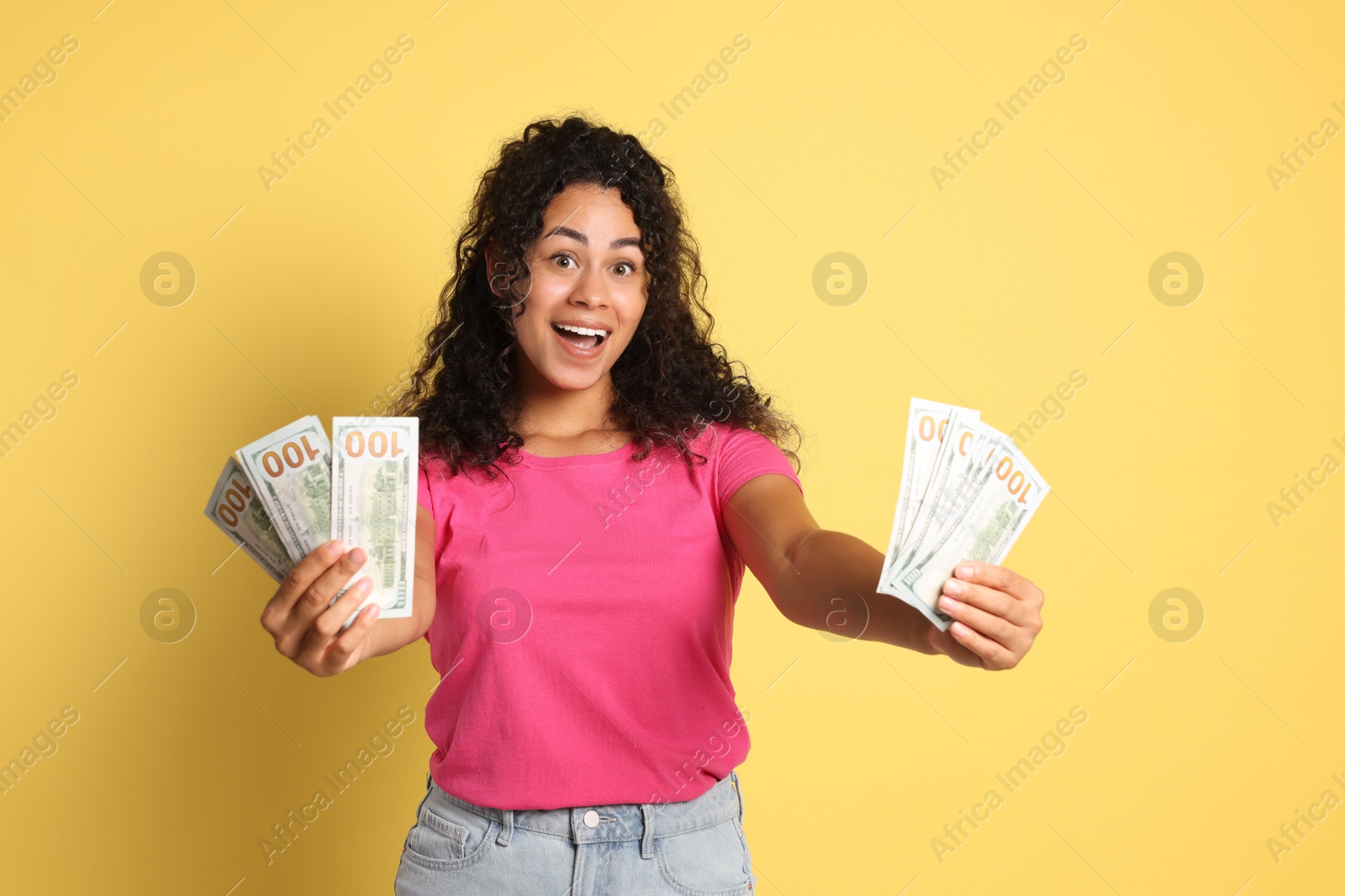 Photo of Happy woman with dollar banknotes on yellow background