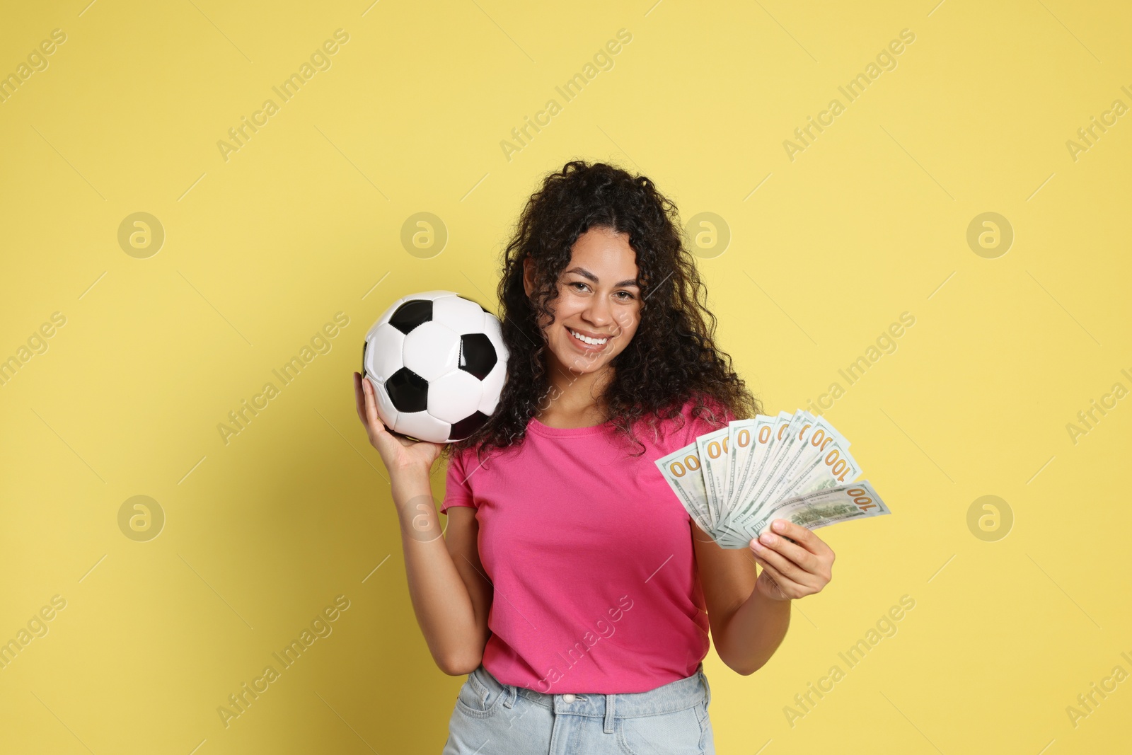 Photo of Happy woman with money and soccer ball on yellow background