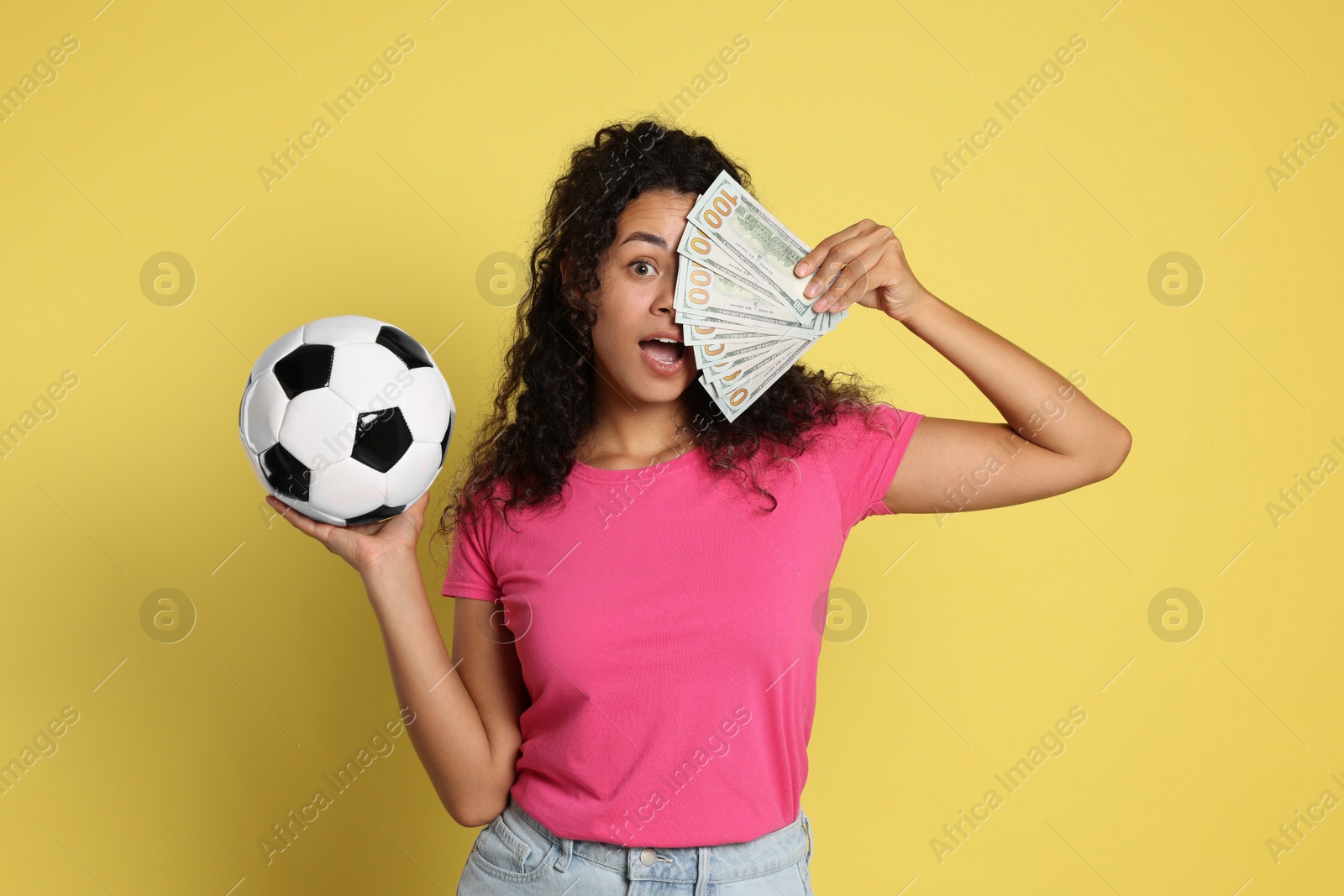 Photo of Shocked woman with money and soccer ball on yellow background