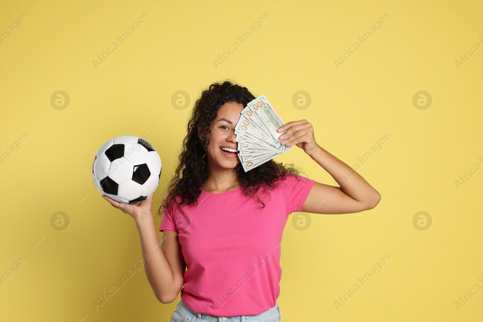 Photo of Happy woman with money and soccer ball on yellow background