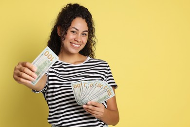 Photo of Happy woman with dollar banknotes on yellow background, space for text