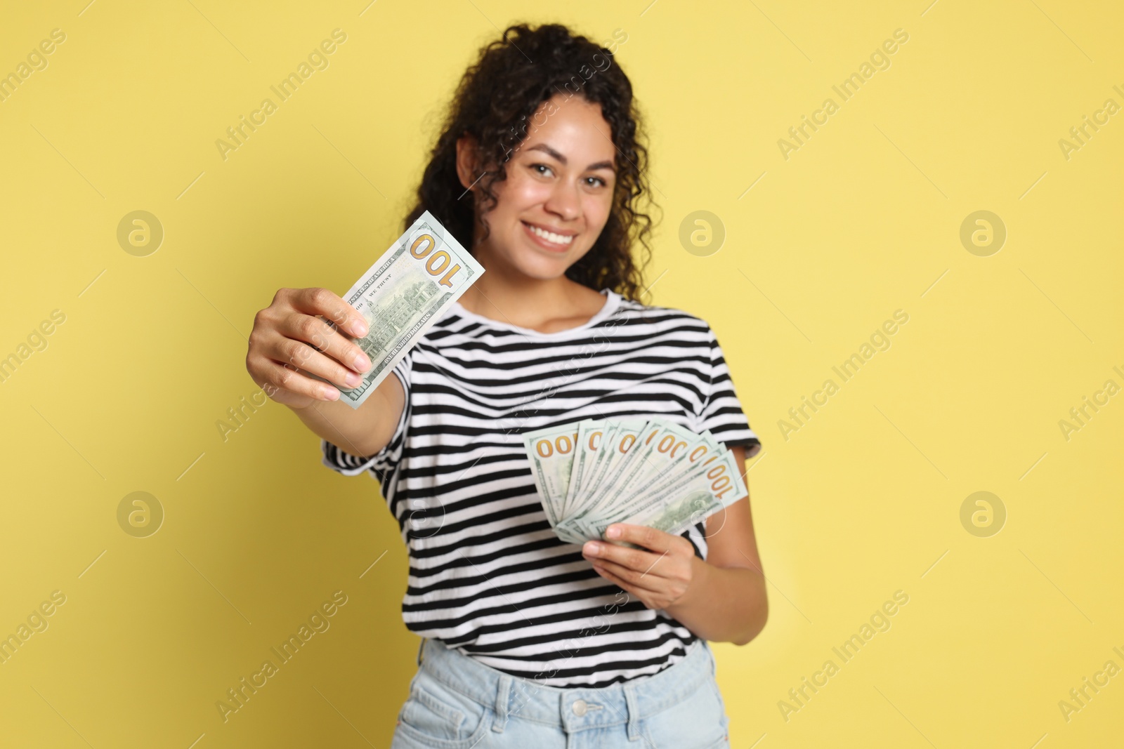 Photo of Happy woman with dollar banknotes on yellow background