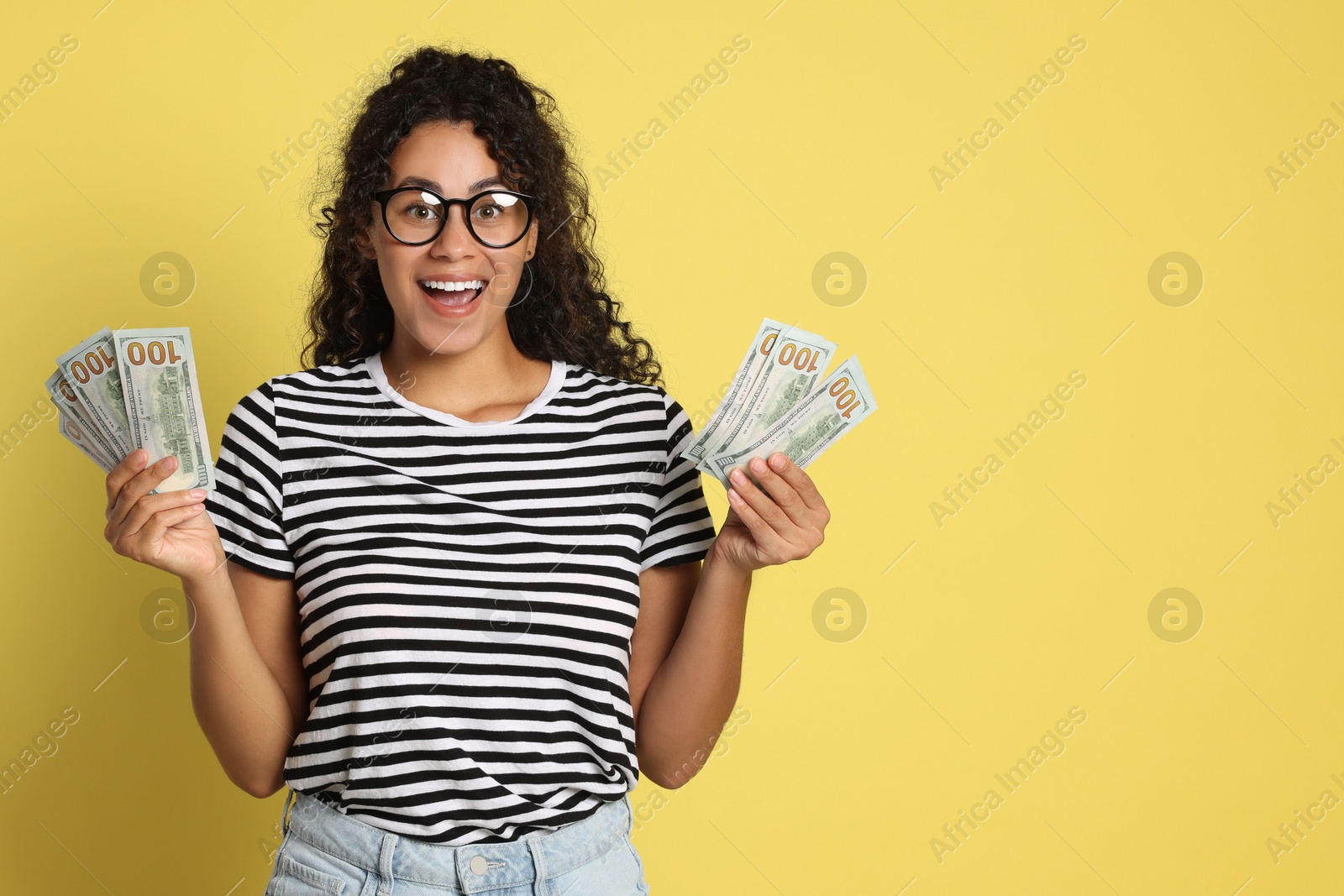 Photo of Happy woman with dollar banknotes on yellow background, space for text