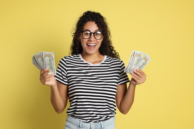 Happy woman with dollar banknotes on yellow background