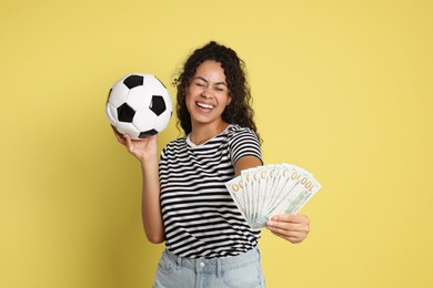 Photo of Happy woman with money and soccer ball on yellow background