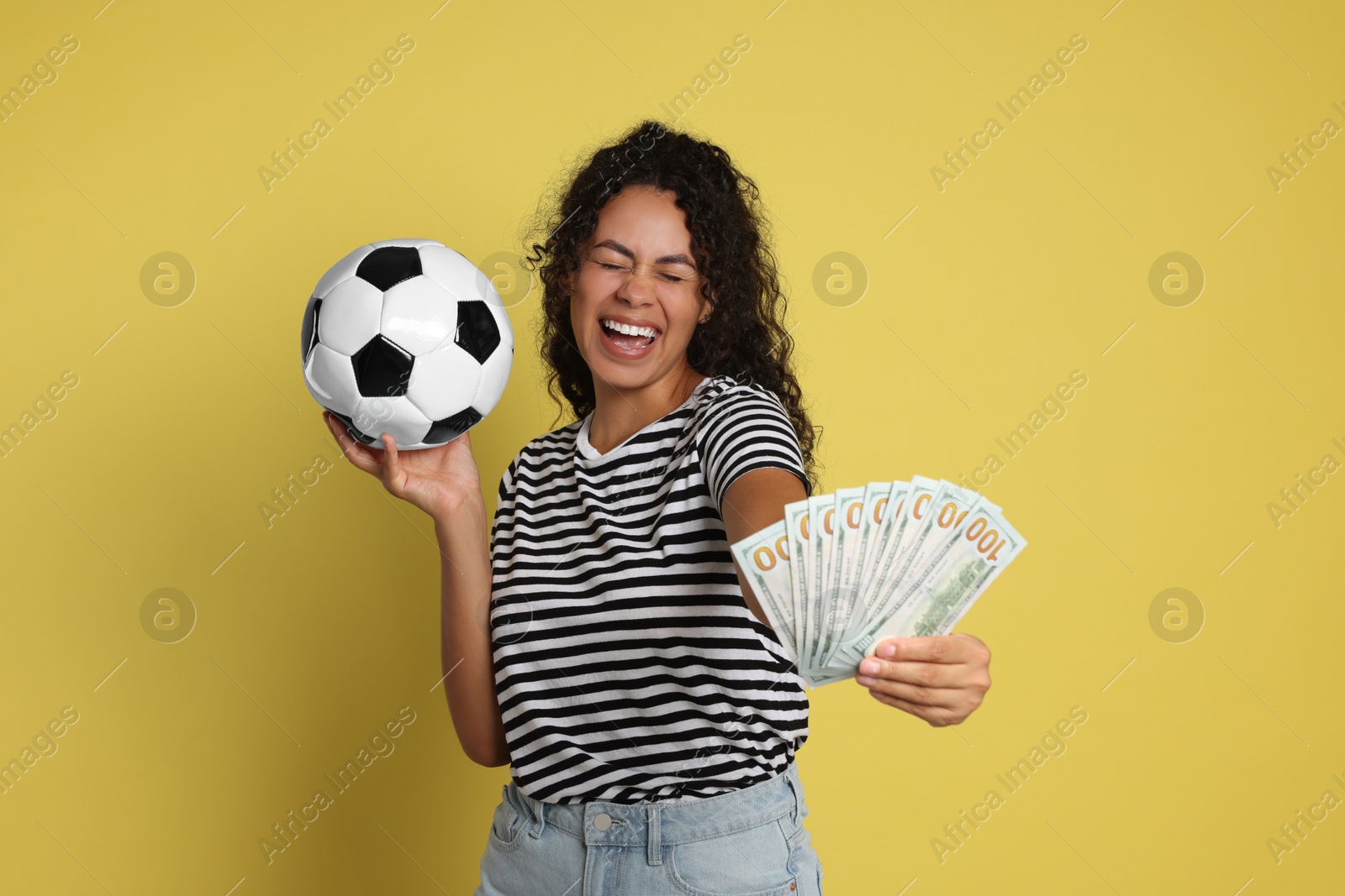 Photo of Happy woman with money and soccer ball on yellow background