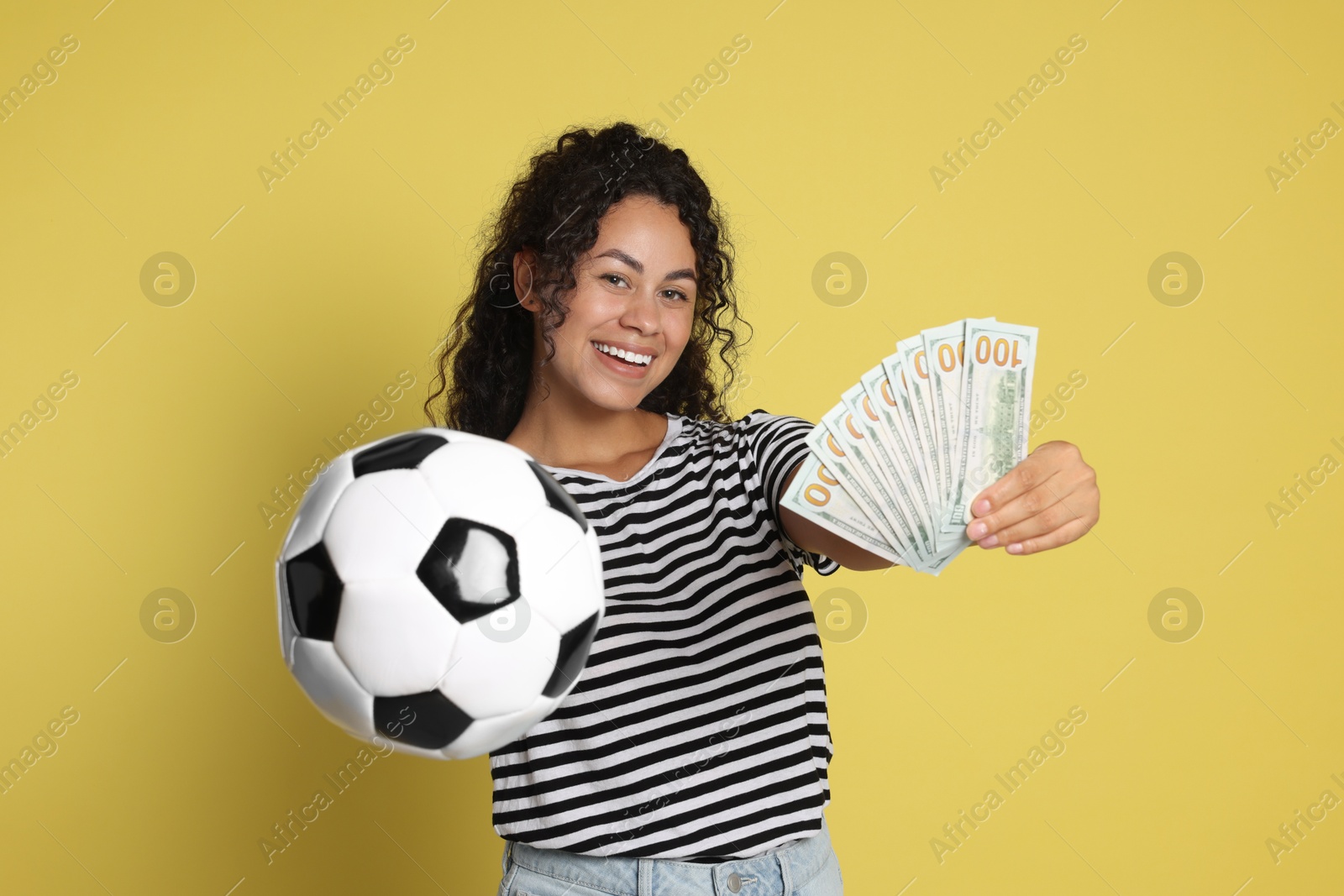 Photo of Happy woman with money and soccer ball on yellow background