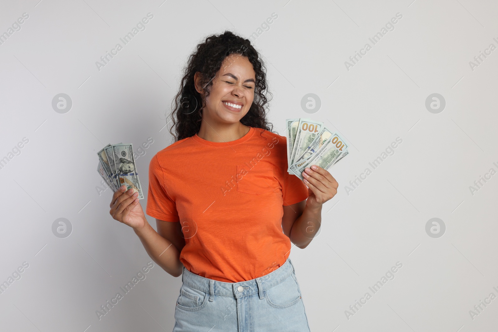 Photo of Happy woman with dollar banknotes on light grey background