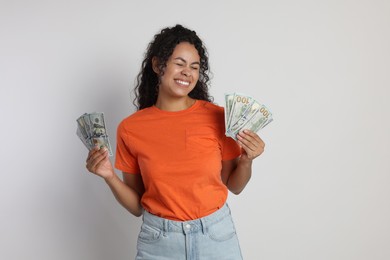 Happy woman with dollar banknotes on light grey background