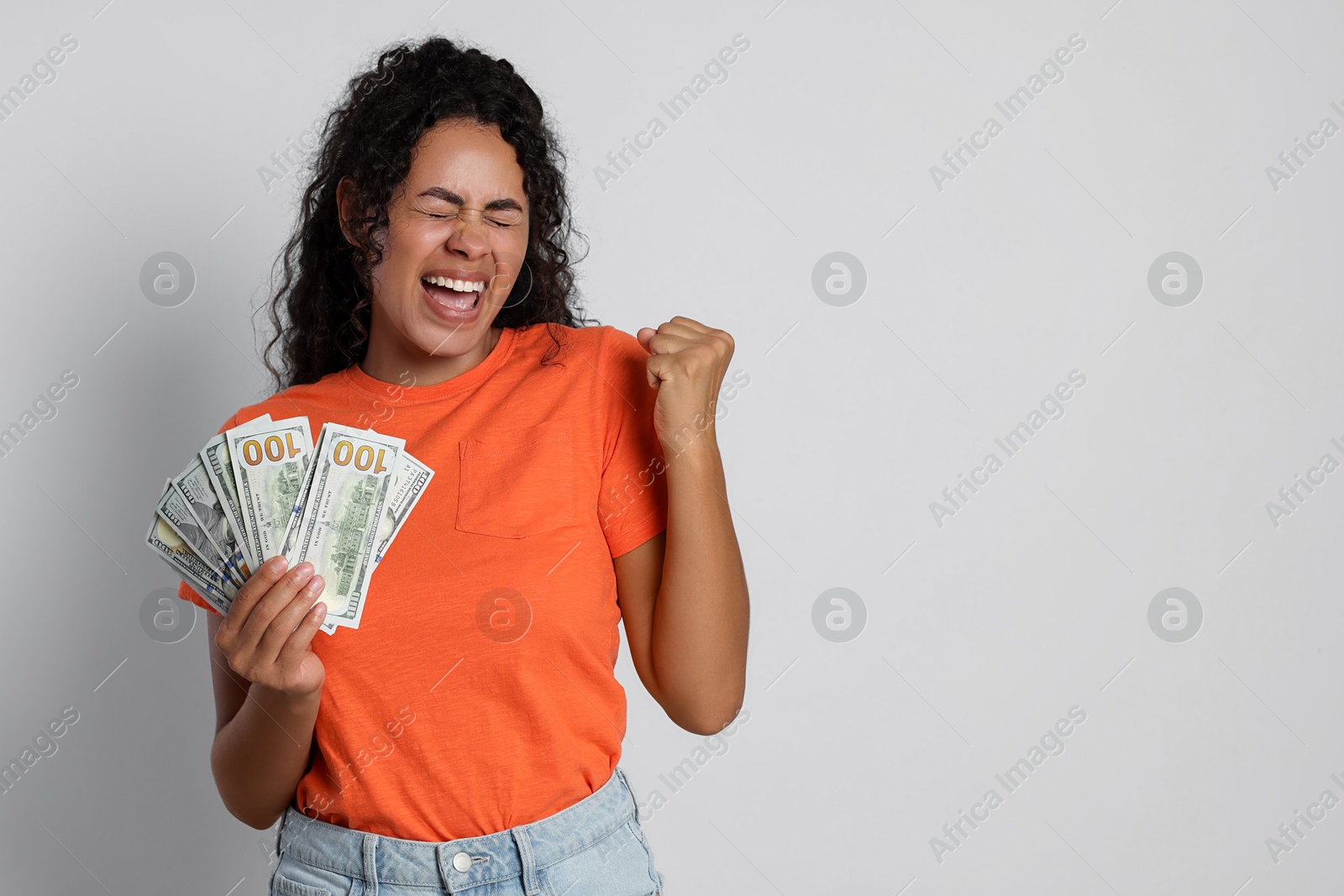 Photo of Happy woman with dollar banknotes on light grey background, space for text