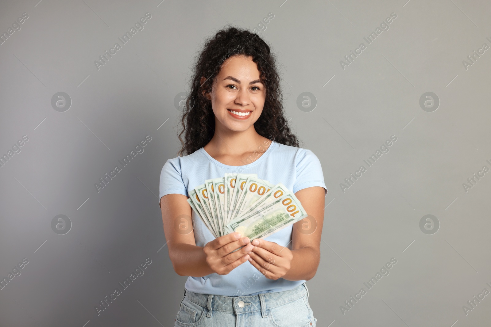 Photo of Happy woman with dollar banknotes on grey background