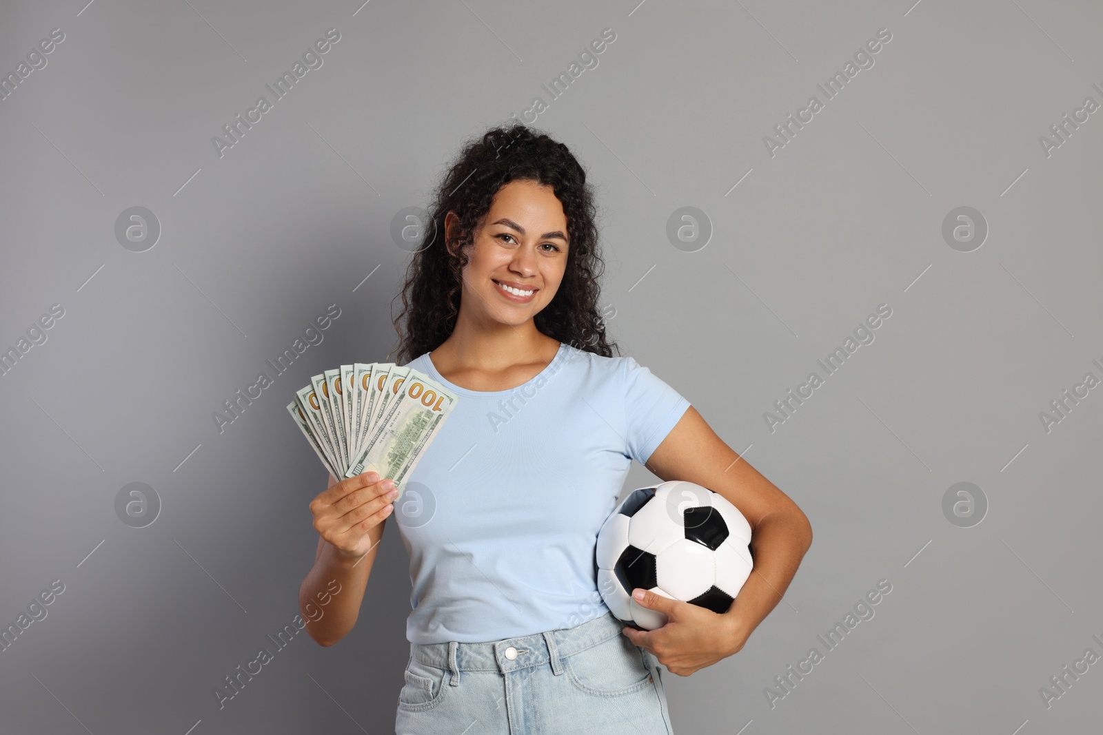 Photo of Happy woman with money and soccer ball on grey background