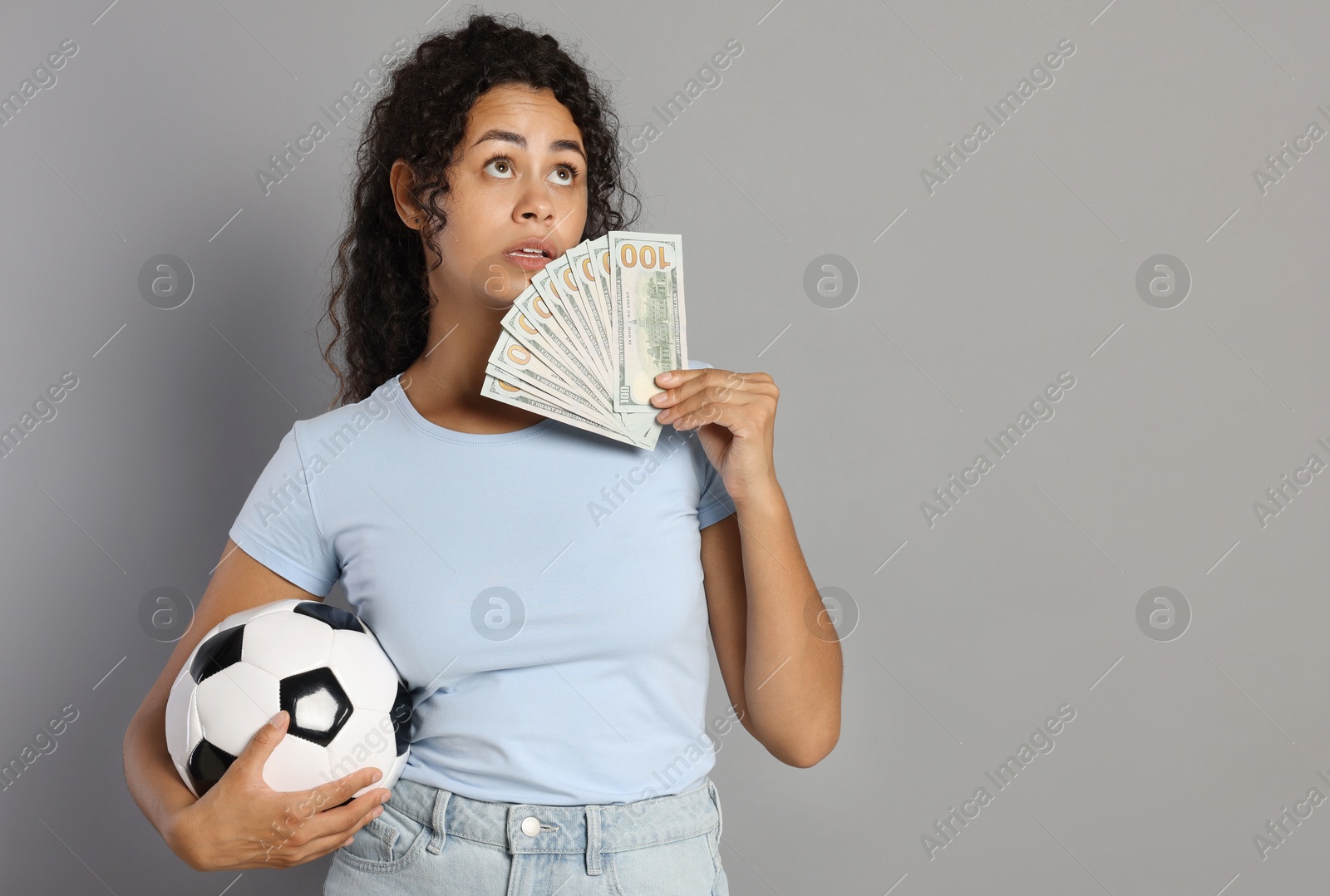 Photo of Woman with money and soccer ball on grey background, space for text