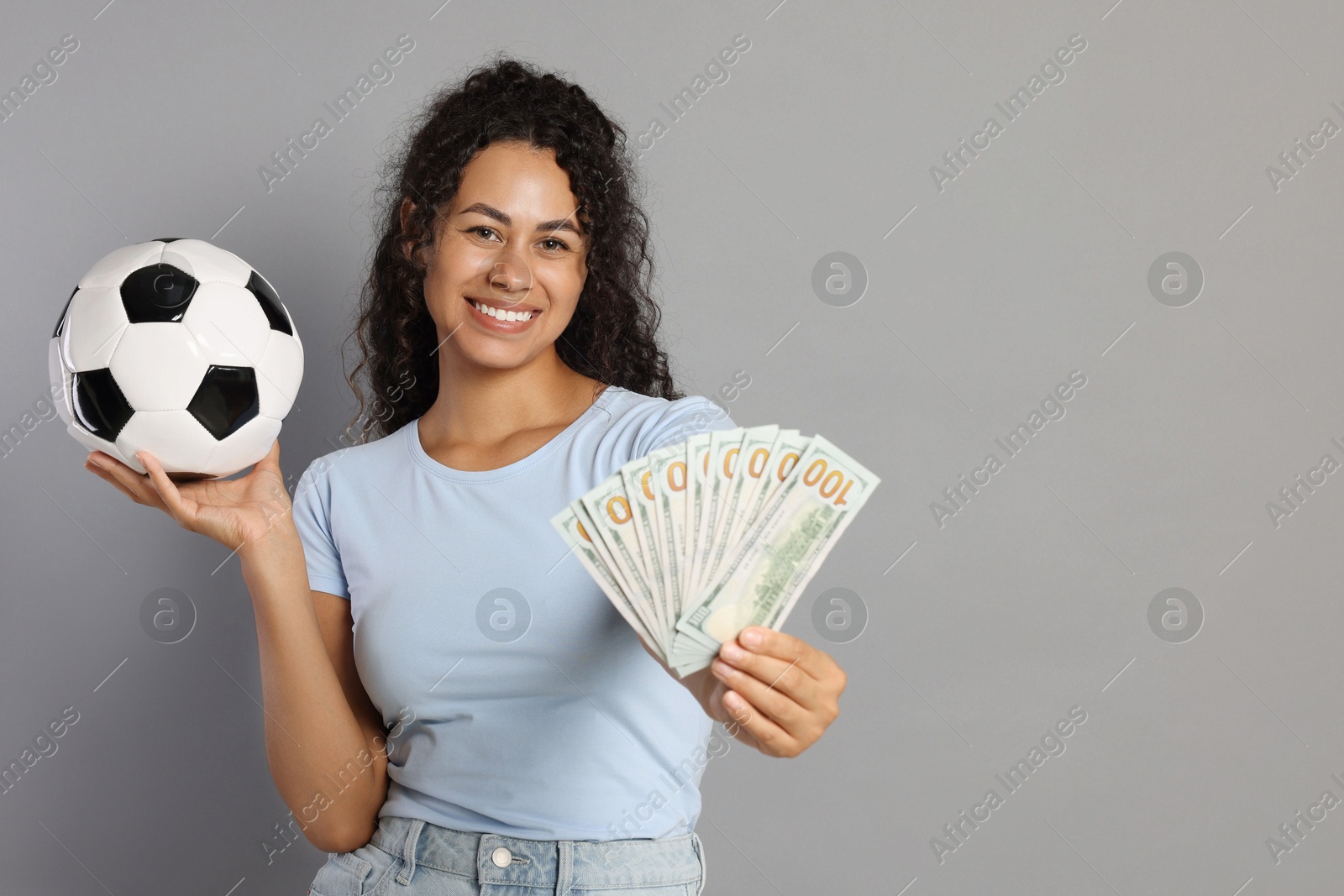 Photo of Happy woman with money and soccer ball on grey background, space for text