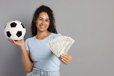 Photo of Happy woman with money and soccer ball on grey background, space for text