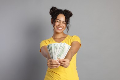 Happy woman with dollar banknotes on grey background