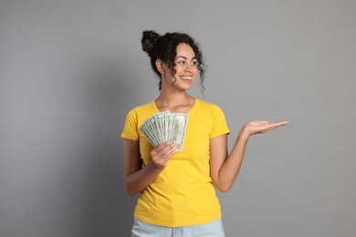 Happy woman with dollar banknotes on grey background