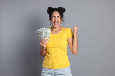 Happy woman with dollar banknotes on grey background