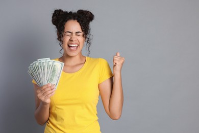 Photo of Happy woman with dollar banknotes on grey background, space for text