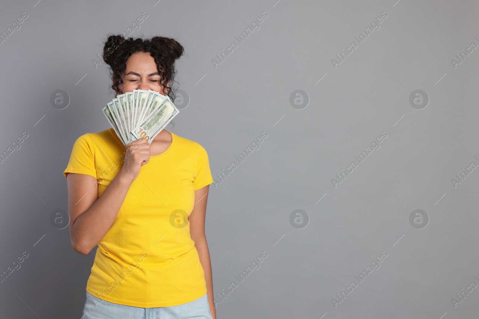 Photo of Woman with dollar banknotes on grey background, space for text