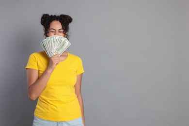 Photo of Woman with dollar banknotes on grey background, space for text