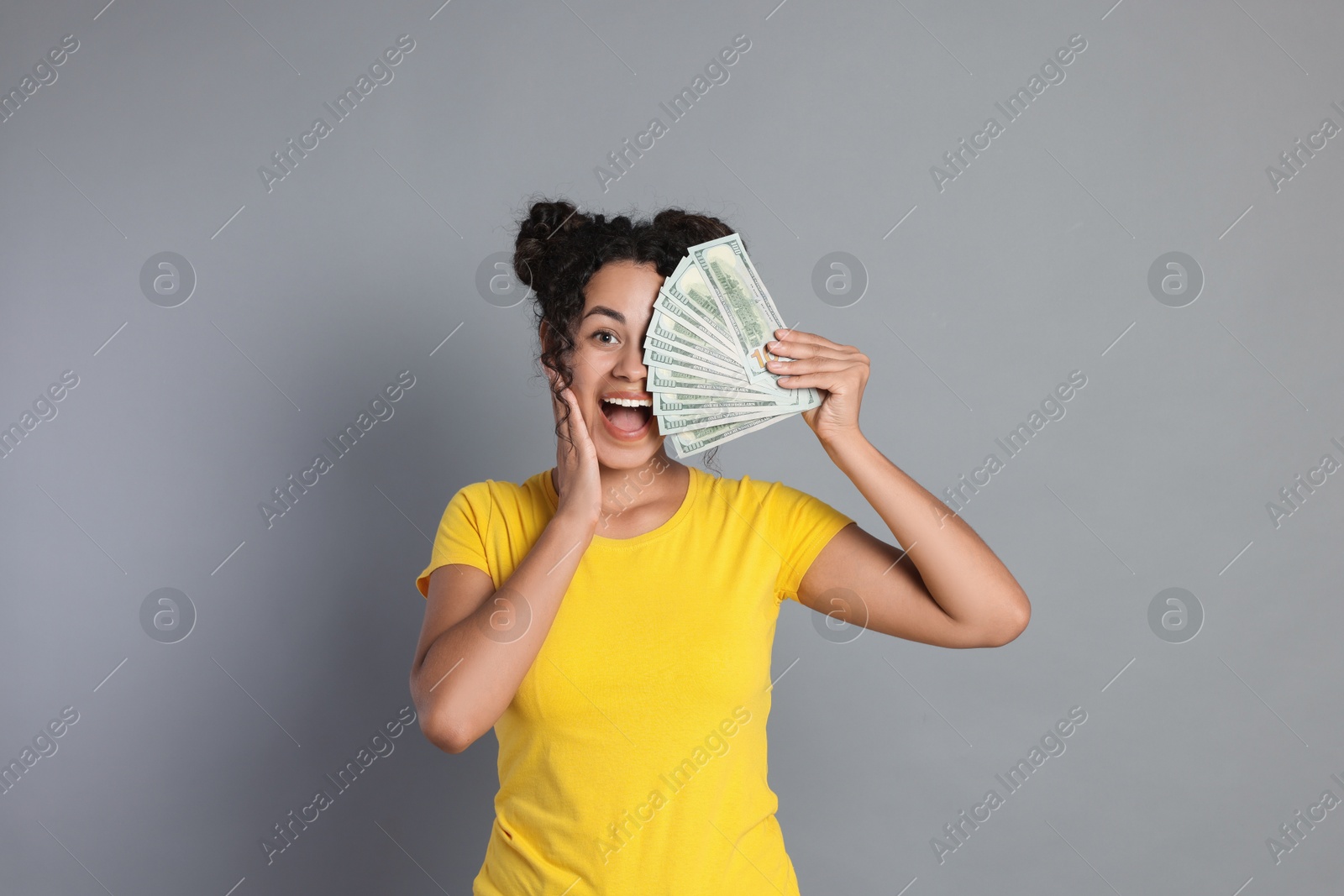 Photo of Happy woman with dollar banknotes on grey background