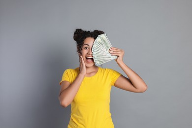 Happy woman with dollar banknotes on grey background