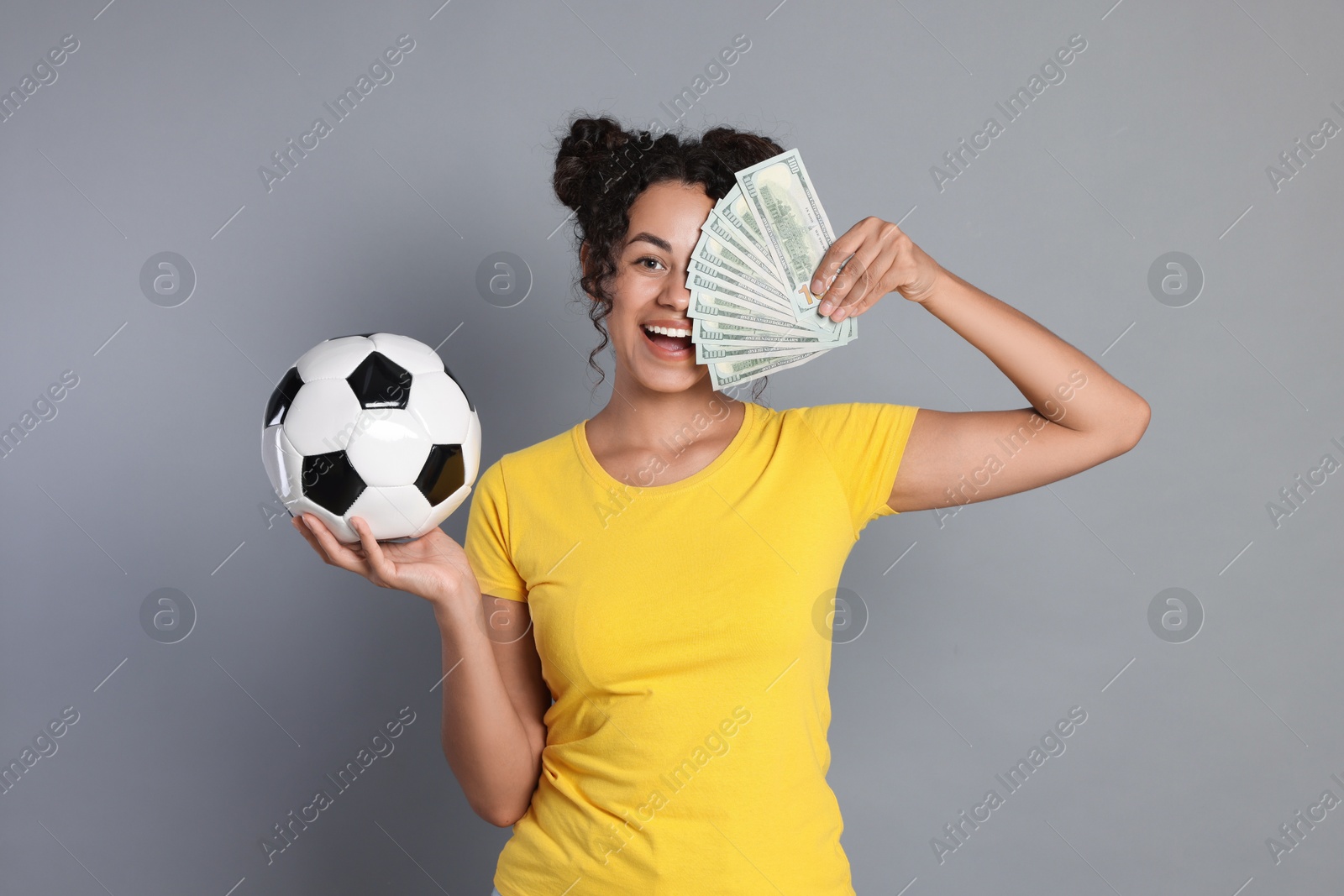 Photo of Happy woman with money and soccer ball on grey background