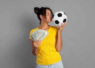 Photo of Happy woman with money and soccer ball on grey background