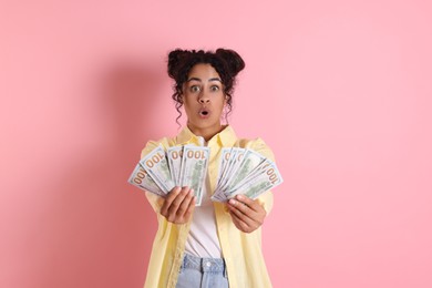 Photo of Shocked woman with dollar banknotes on pink background