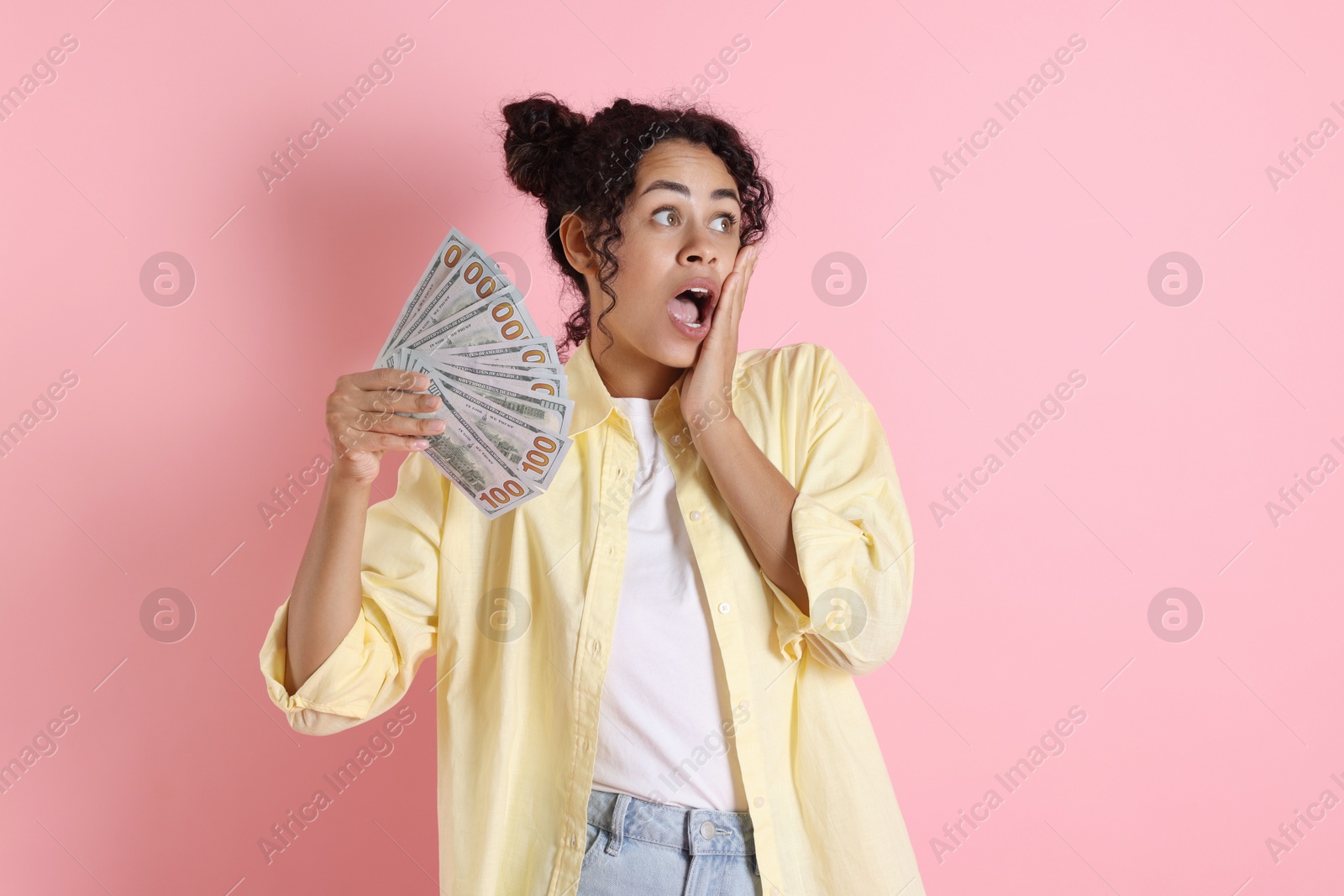 Photo of Shocked woman with dollar banknotes on pink background