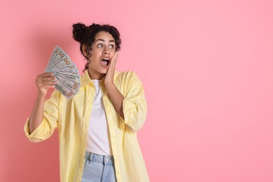 Shocked woman with dollar banknotes on pink background, space for text