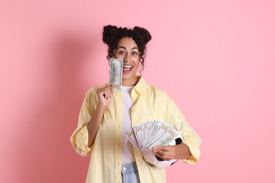 Happy woman with money and soccer ball on pink background