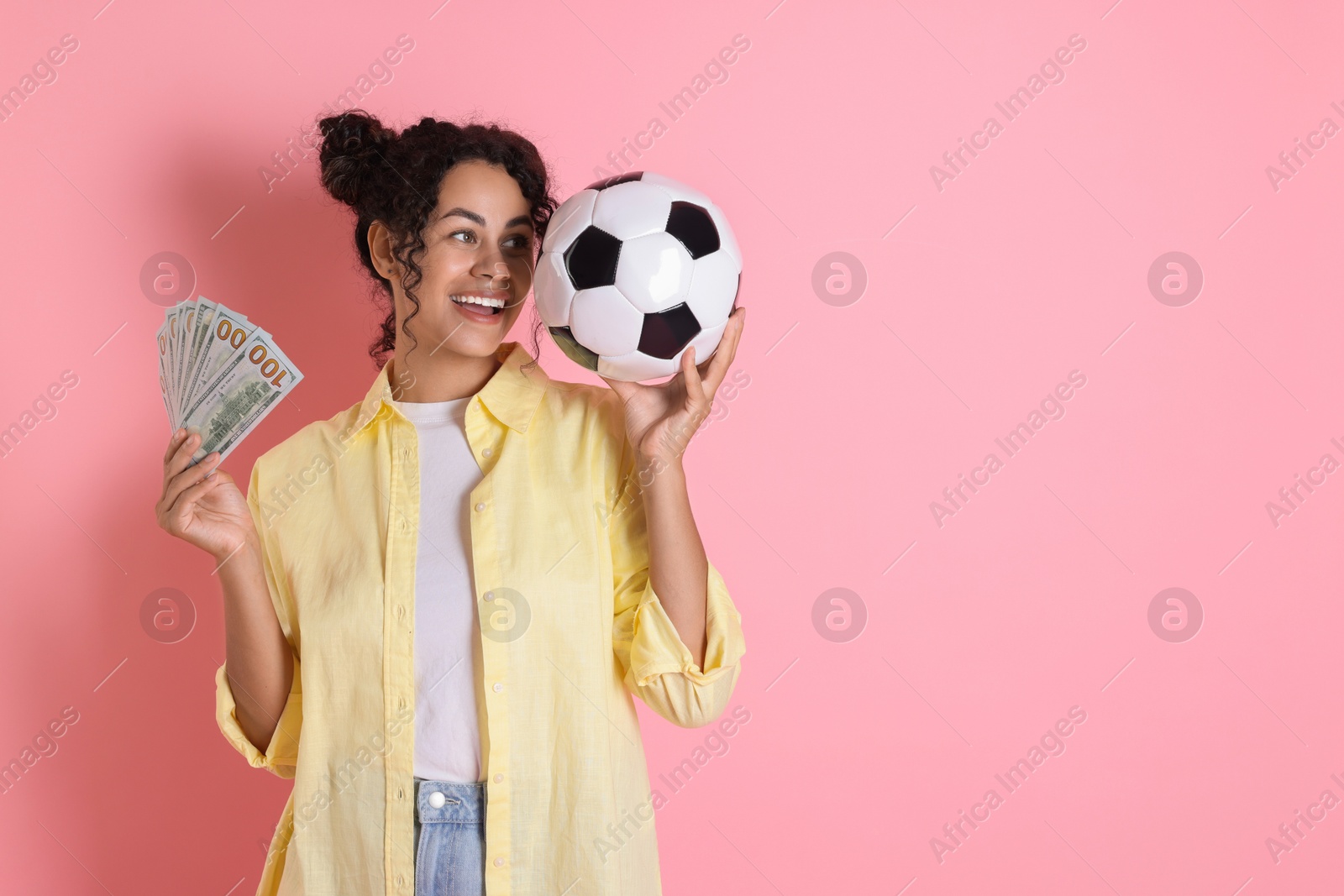 Photo of Happy woman with money and soccer ball on pink background, space for text